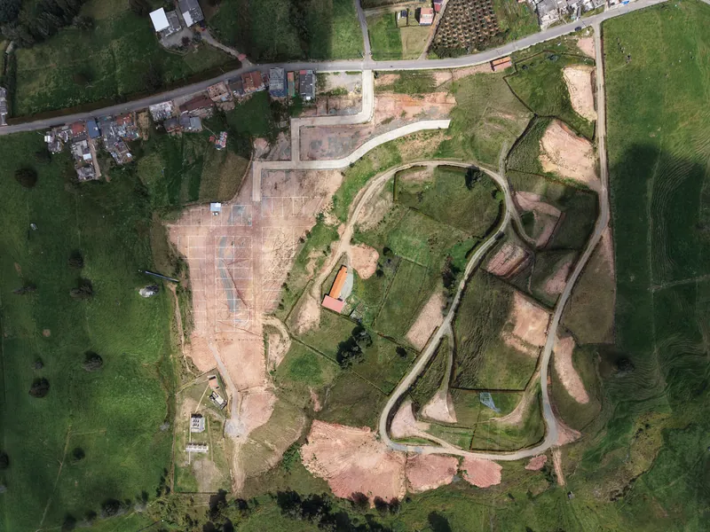 Foto de dron de todo San Julián desde el aire: a la izquierda el loteo urbano con los lotes marcados en cal, arriba la calle del pueblo y a la derecha la vía en curva de San Julián Campestre